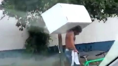 Man Carries a Fidge on a Bike