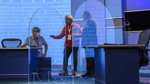 The stage (lit up in bright blue) for the vice presidential debate in Kingsbury Hall of the University of Utah features plexiglass partitions between two desks to prevent the spread of coronavirus....