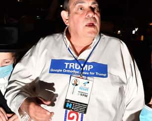 A photo of Heshy Tischler, an Orthodox Jew who lives in Brooklyn’s Borough Park. He is wearing a white pro-Trump shirt and there are masked people around him.