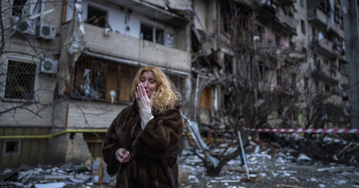 Natali Sevriukova reacts next to her house following a rocket attack