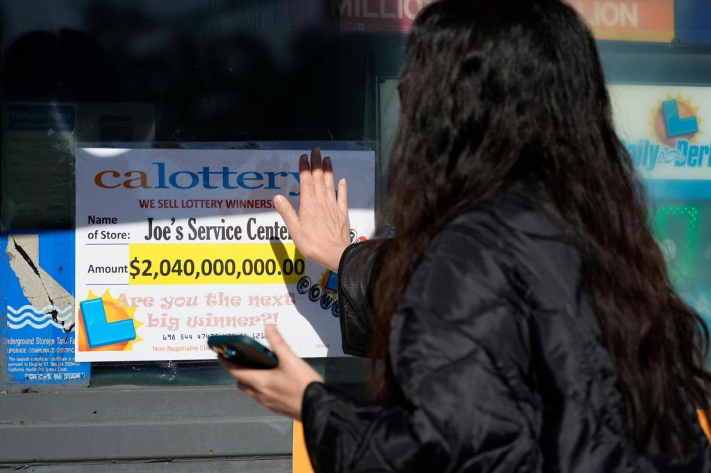 People touch a window sign for good luck announcing the $2.04 billion-winning Powerball ticket award at Joe's Service Center, a Mobil gas station in Altadena, Calif., on Jan. 6, 2023.