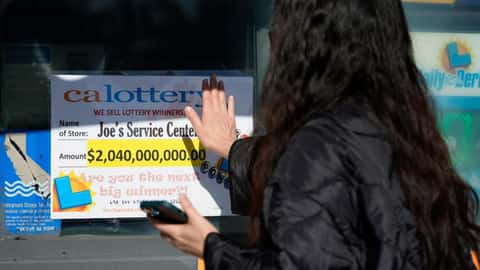People touch a window sign for good luck announcing the $2.04 billion-winning Powerball ticket award at Joe's Service Center, a Mobil gas station in Altadena, Calif., on Jan. 6, 2023.